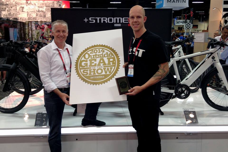 Stromer team accepts the 2014 Outside Gear of the Show award at Interbike, with high-performance e-bikes on display.