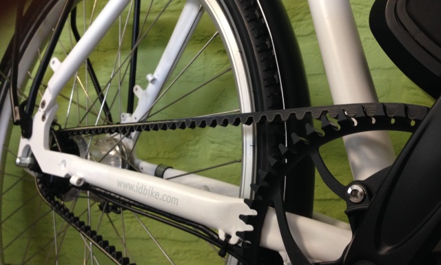 Close-up of an e-bike's belt drive system on a white IDbike frame.