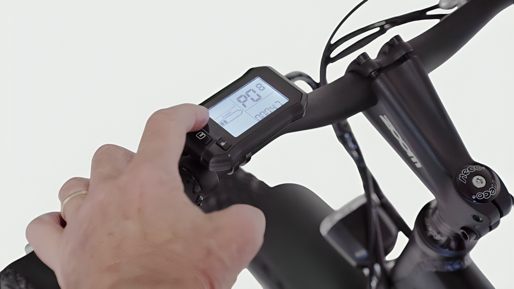 Rider adjusting e-bike display showing speed on handlebars with a clear interface
